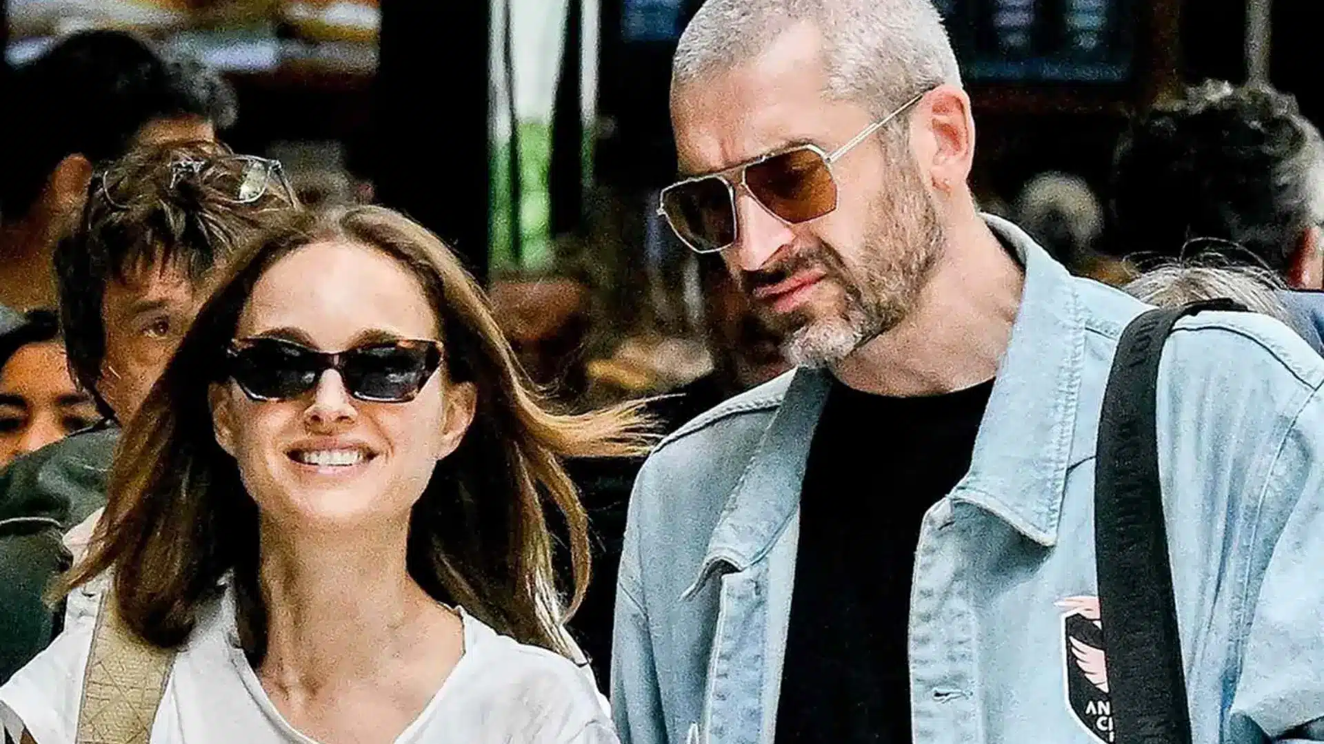 Natalie and Tanguy wearing sunglasses walk together outdoors, with a woman smiling beside a man in casual clothing.
