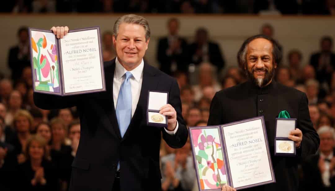 al gore and rajendra pachauri holding their nobel peace prize certificates and medals during the award ceremony