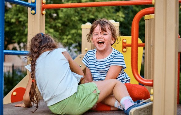 Two girls laughing on the playground.