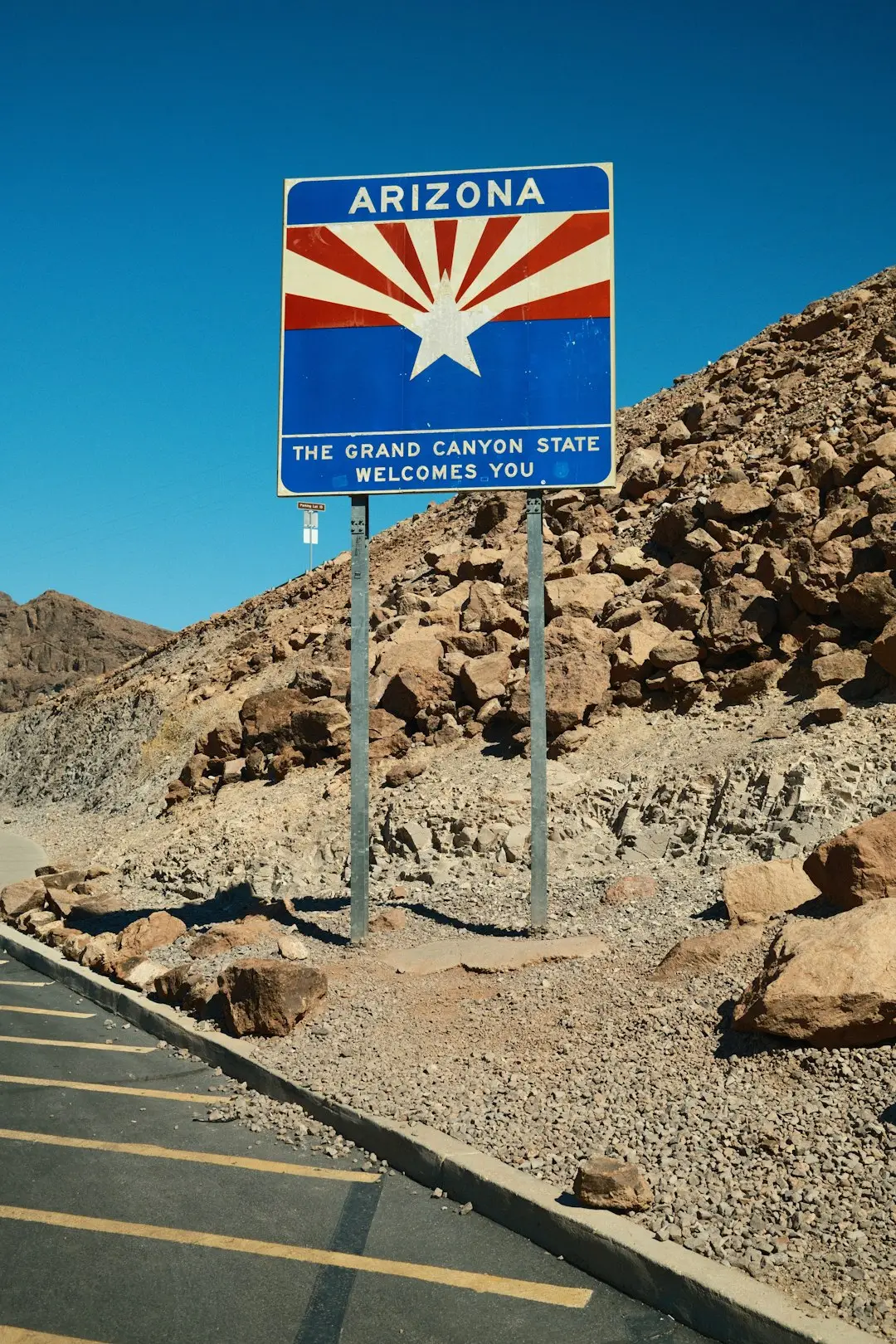 Arizona welcome sign with star design in desert landscape under clear blue sky