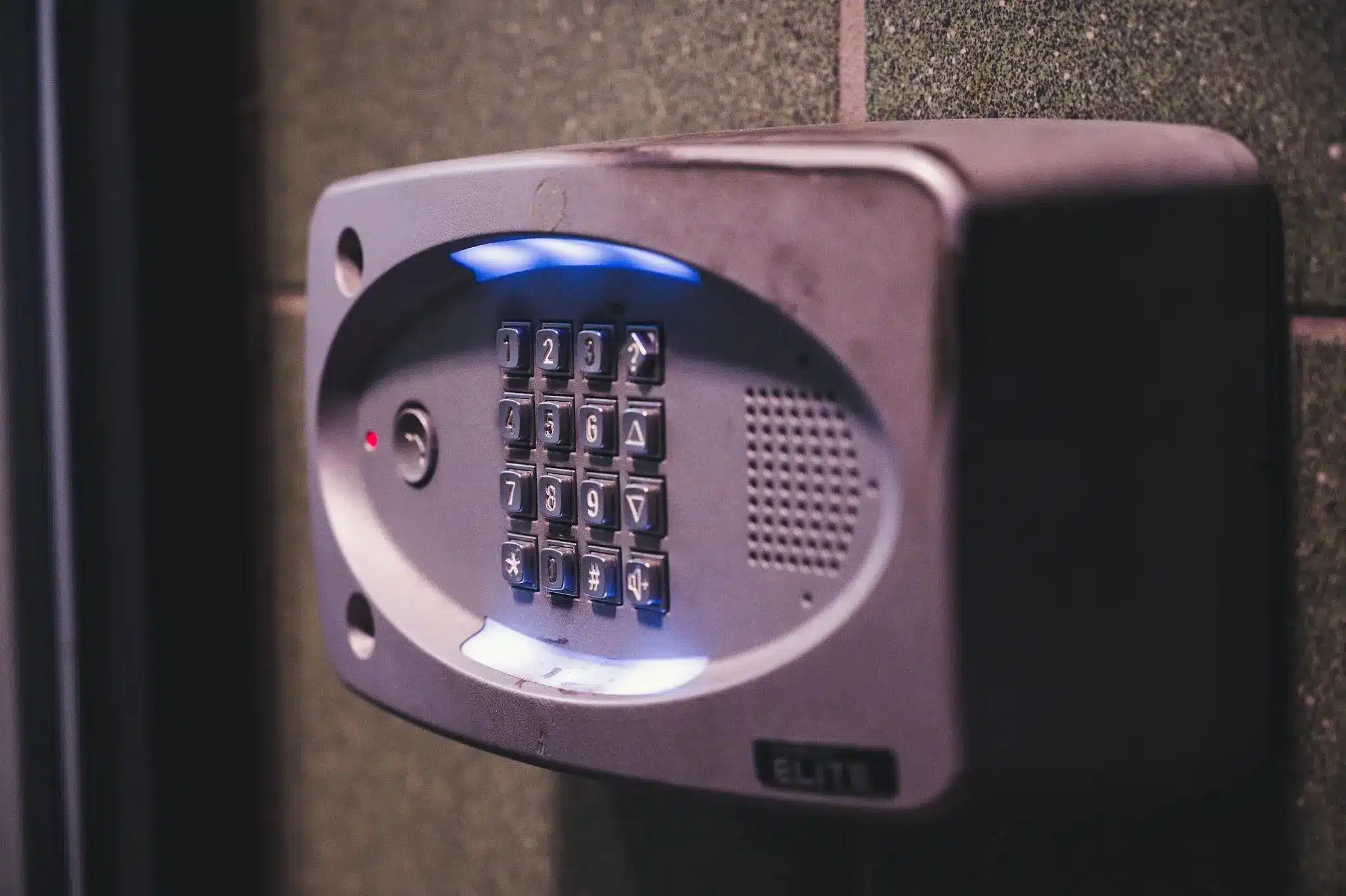 Security keypad with illuminated buttons mounted on tiled wall indoors