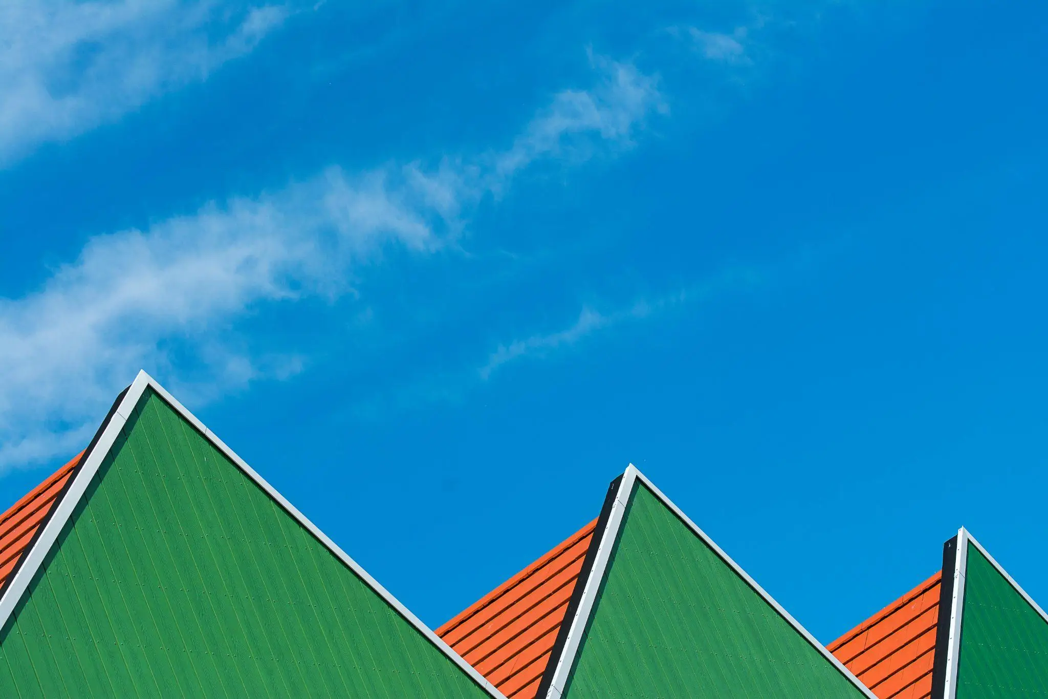 Triangular green and orange rooftops against clear blue sky