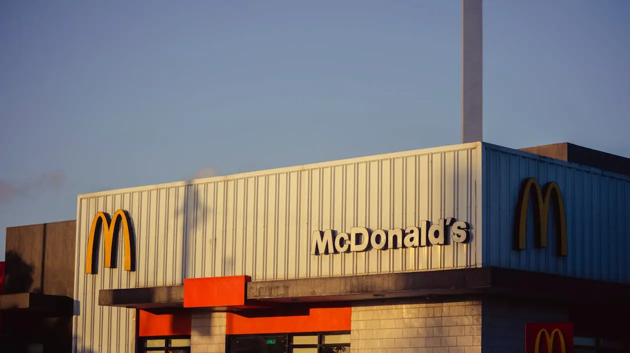 McDonald's restaurant facade with yellow arches under clear blue sky at sunset