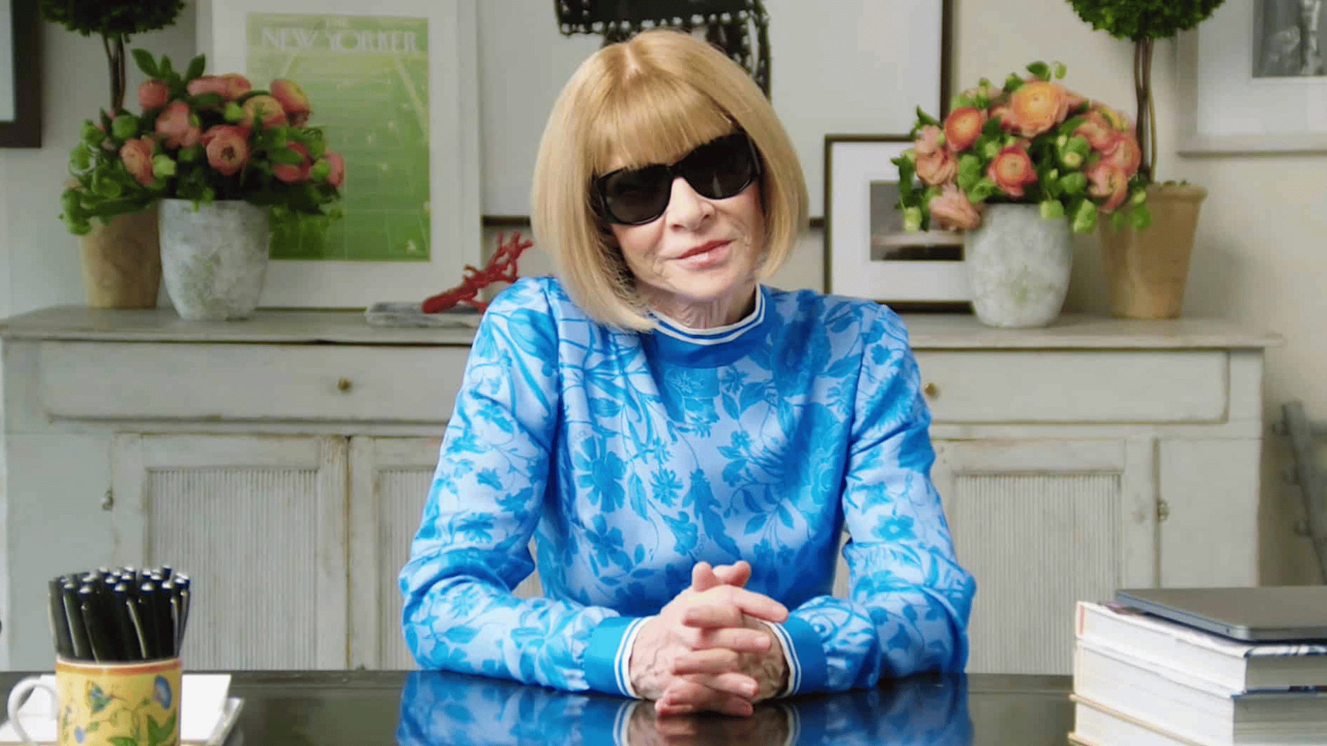 Anna Wintour seated at her work desk, focused and engaged in her tasks