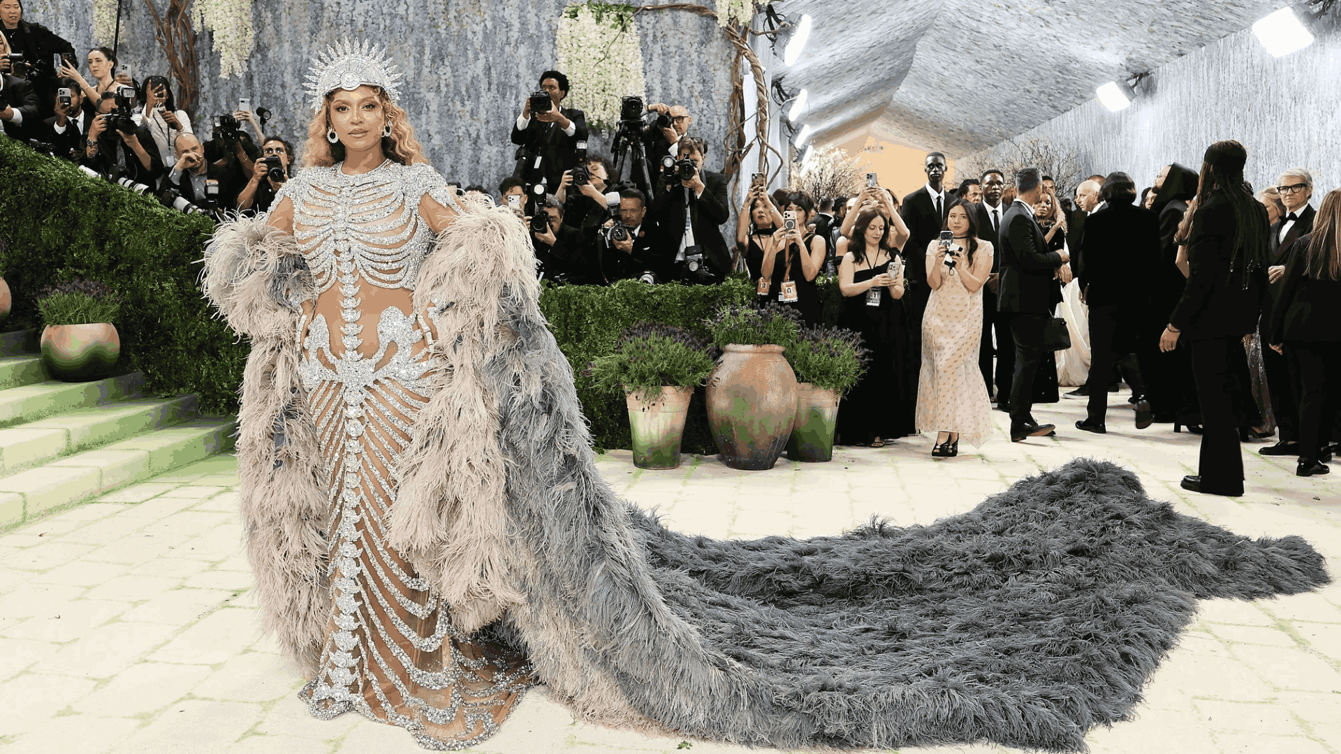 Beyoncé in a dazzling silver gown with a dramatic feathered train at the Met Gala.