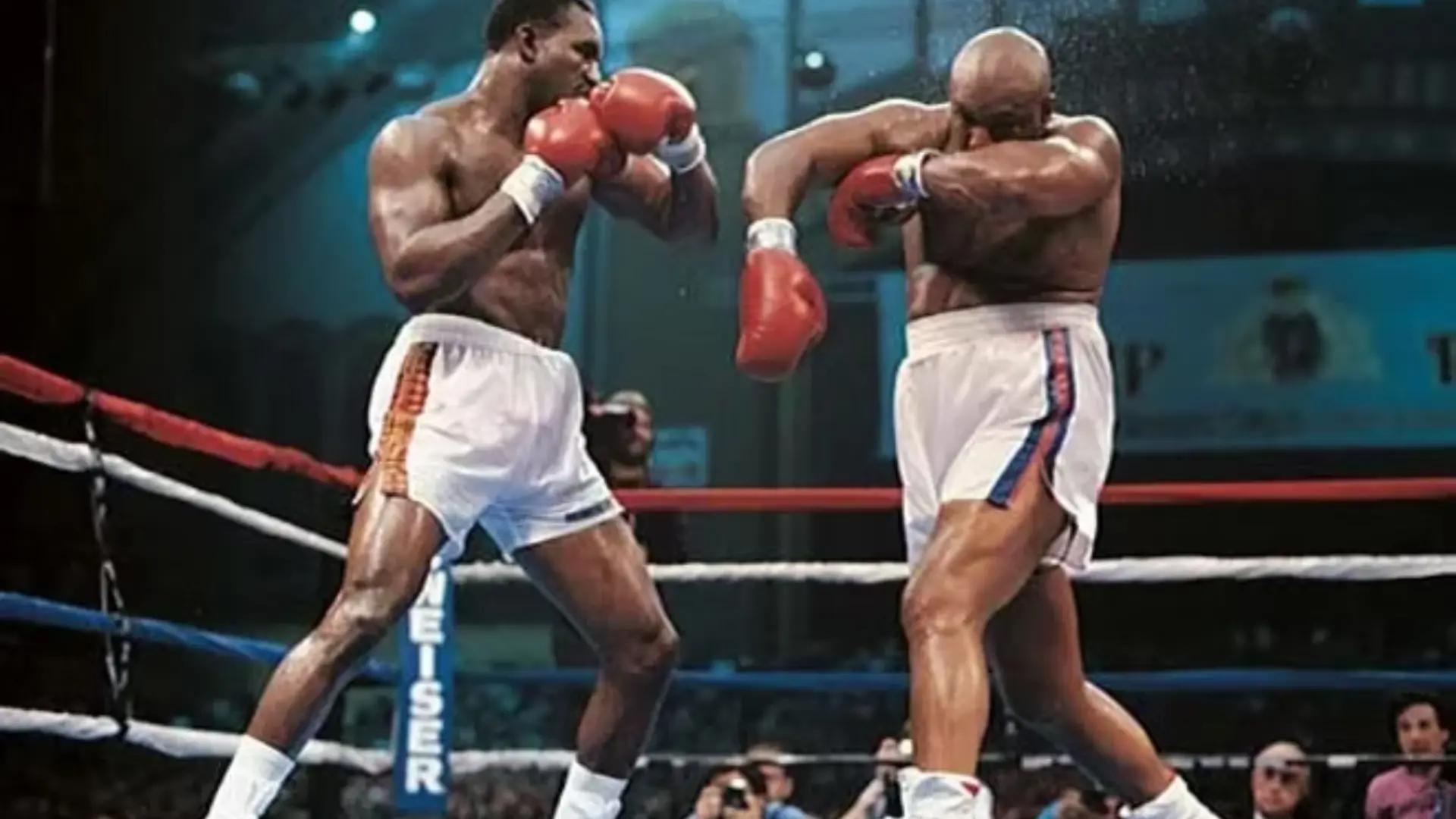 Evander Holyfield throws a punch at his opponent during an intense boxing match inside a packed arena