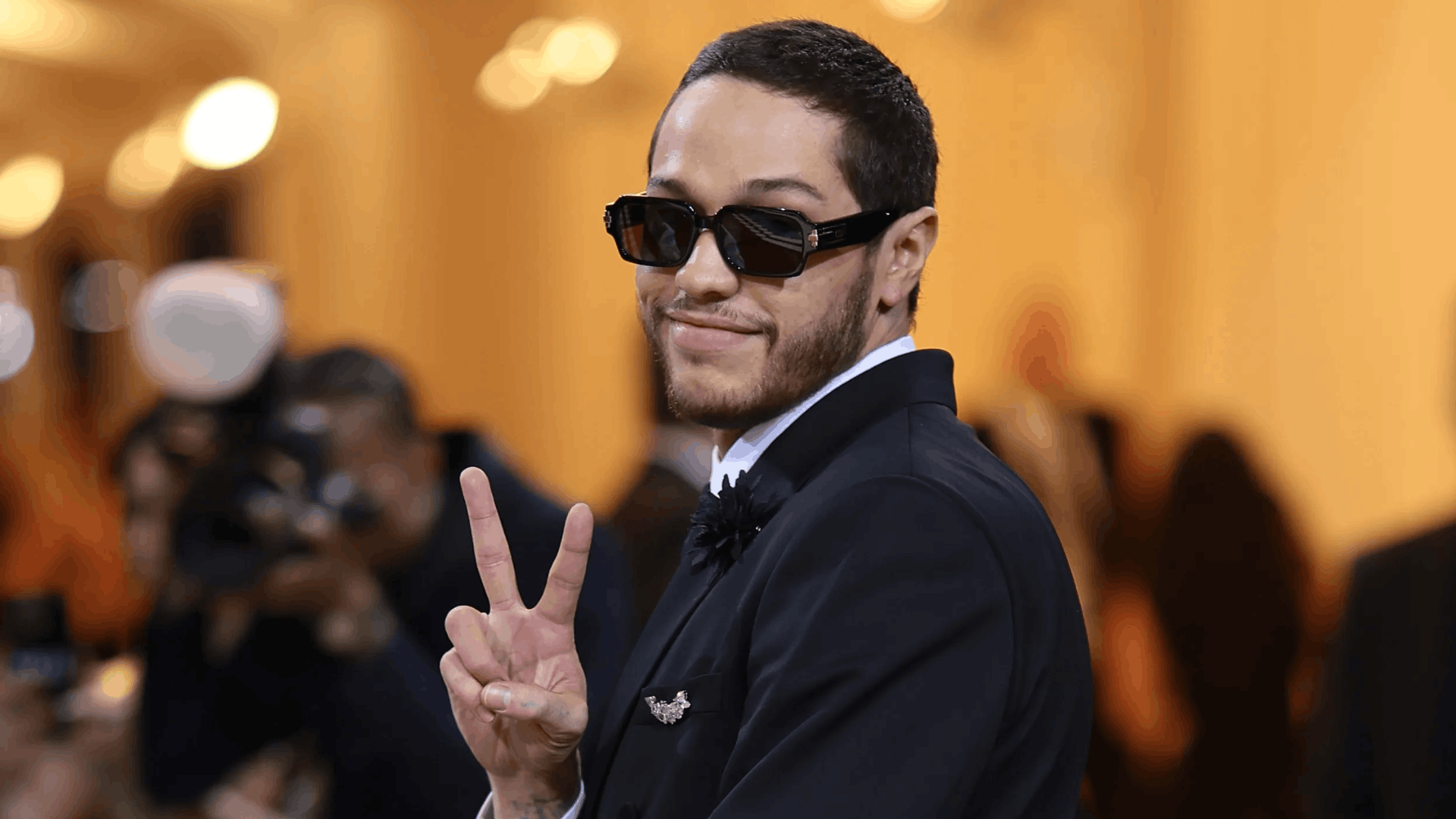 Pete Davidson posing in a formal event wearing a tuxedo.