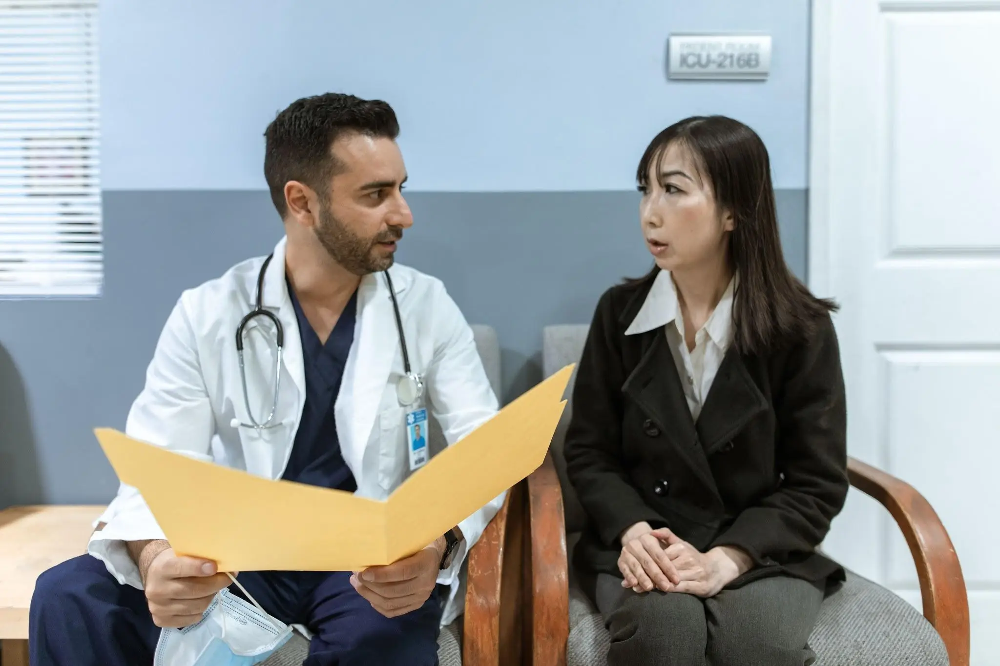 Doctor discussing medical documents with woman in hospital waiting area
