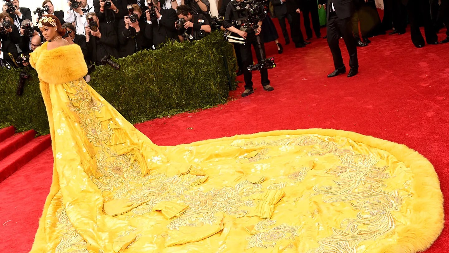 Rihanna wearing the iconic yellow Guo Pei gown at the 2015 Met Gala, a groundbreaking look that redefined red carpet fashion and set a new standard for themed dressing