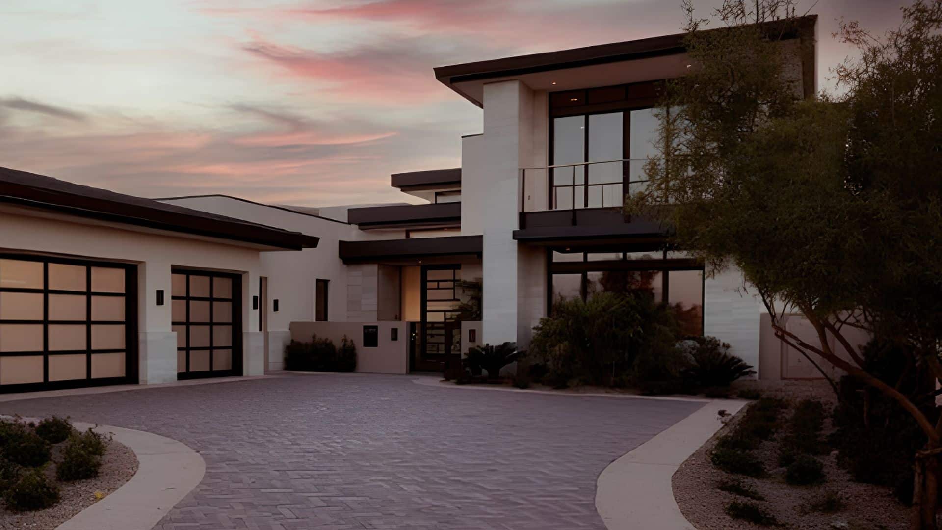 Mark Wahlberg’s Las Vegas residence at The Summit Club, showing a modern luxury home with expansive windows, landscaped grounds, and a view of the city skyline under a clear sky.