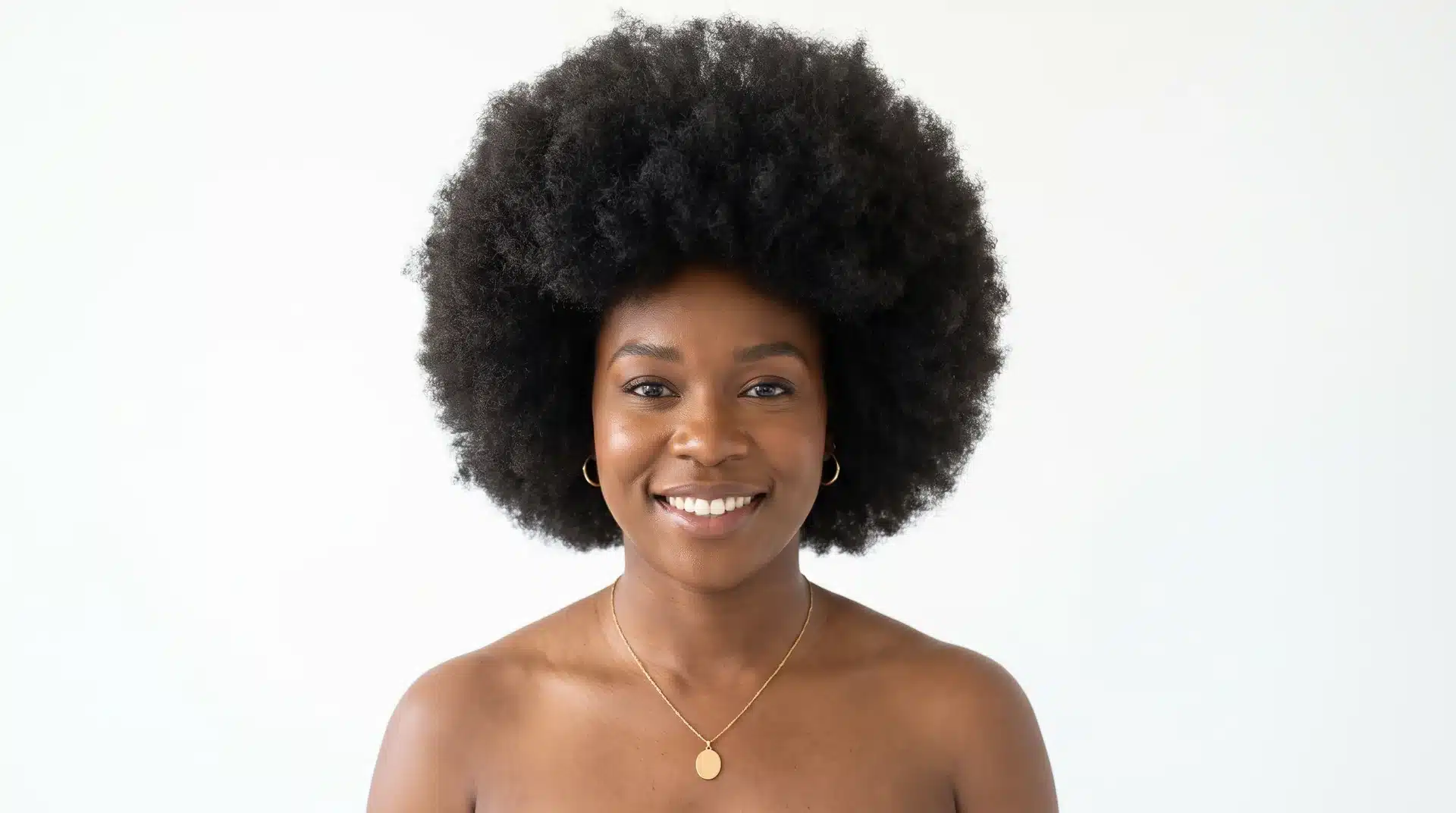 Black woman with a full rounded natural afro picked for height in bright natural light.