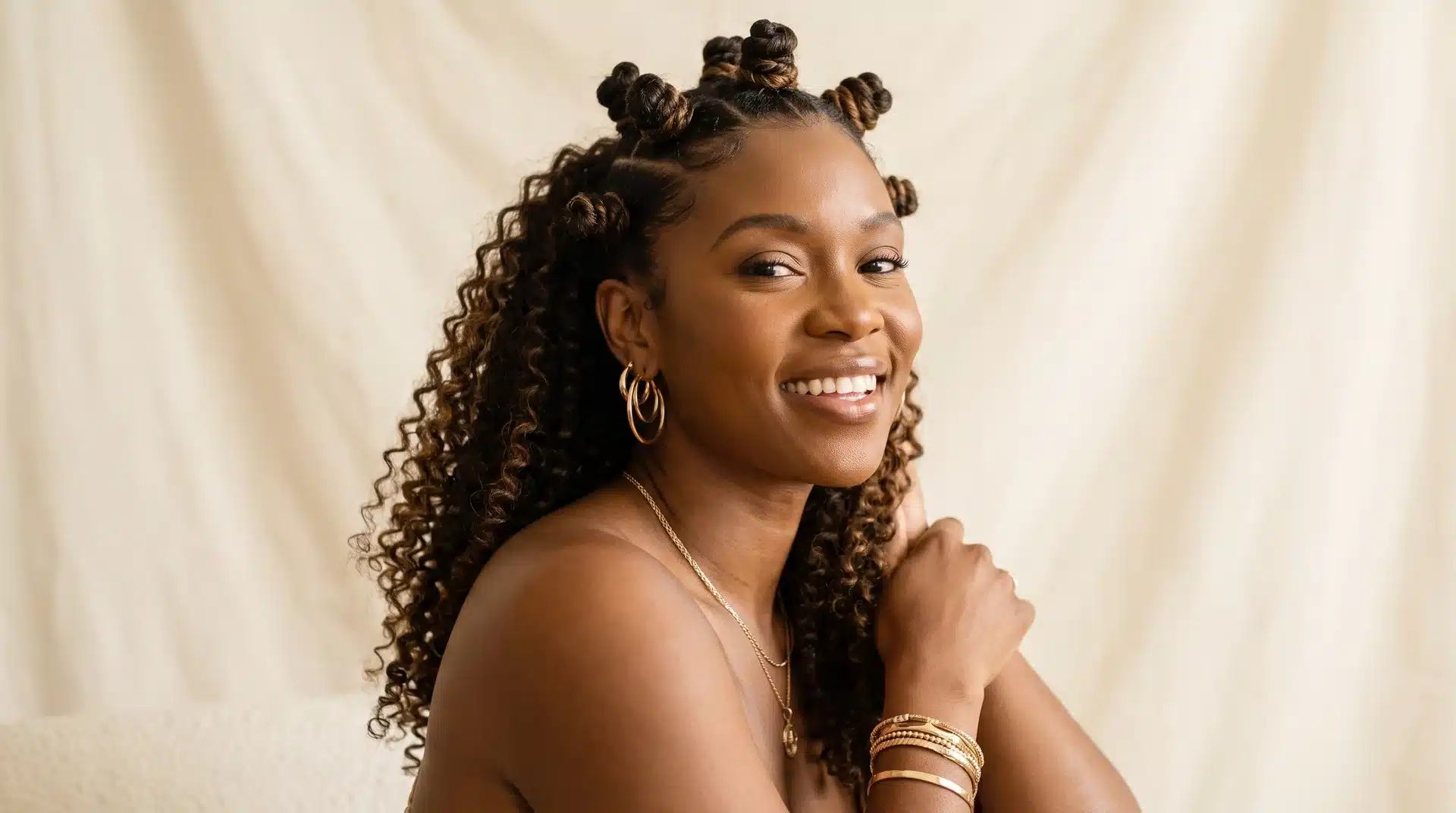 Black woman with mini Bantu knots mixed with loose curls in a half-up style.