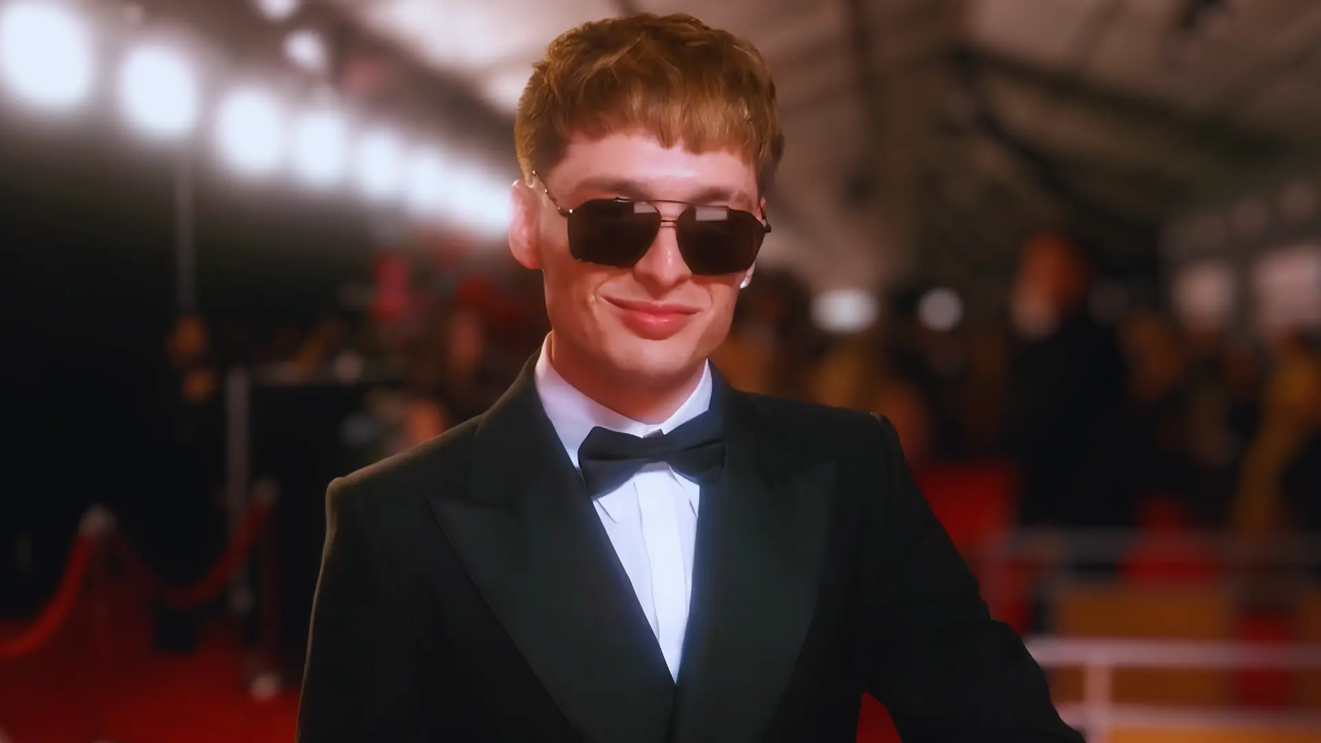 Peso Pluma debuting his new honey blonde haircut and dark sunglasses on the 2025 Grammy Awards red carpet.