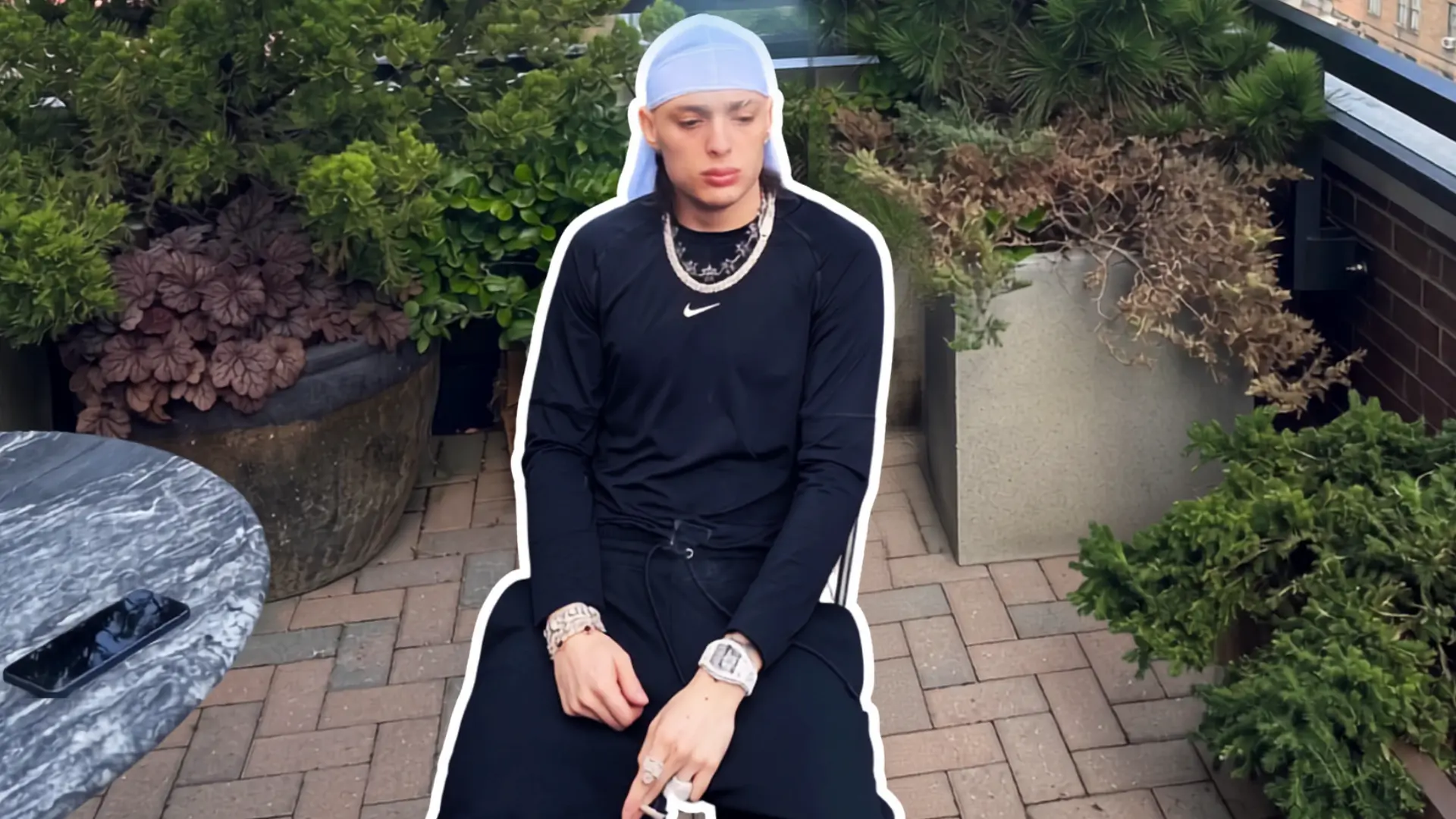 Peso Pluma wearing a light blue durag on a rooftop terrace, concealing his new haircut before the Grammy reveal.