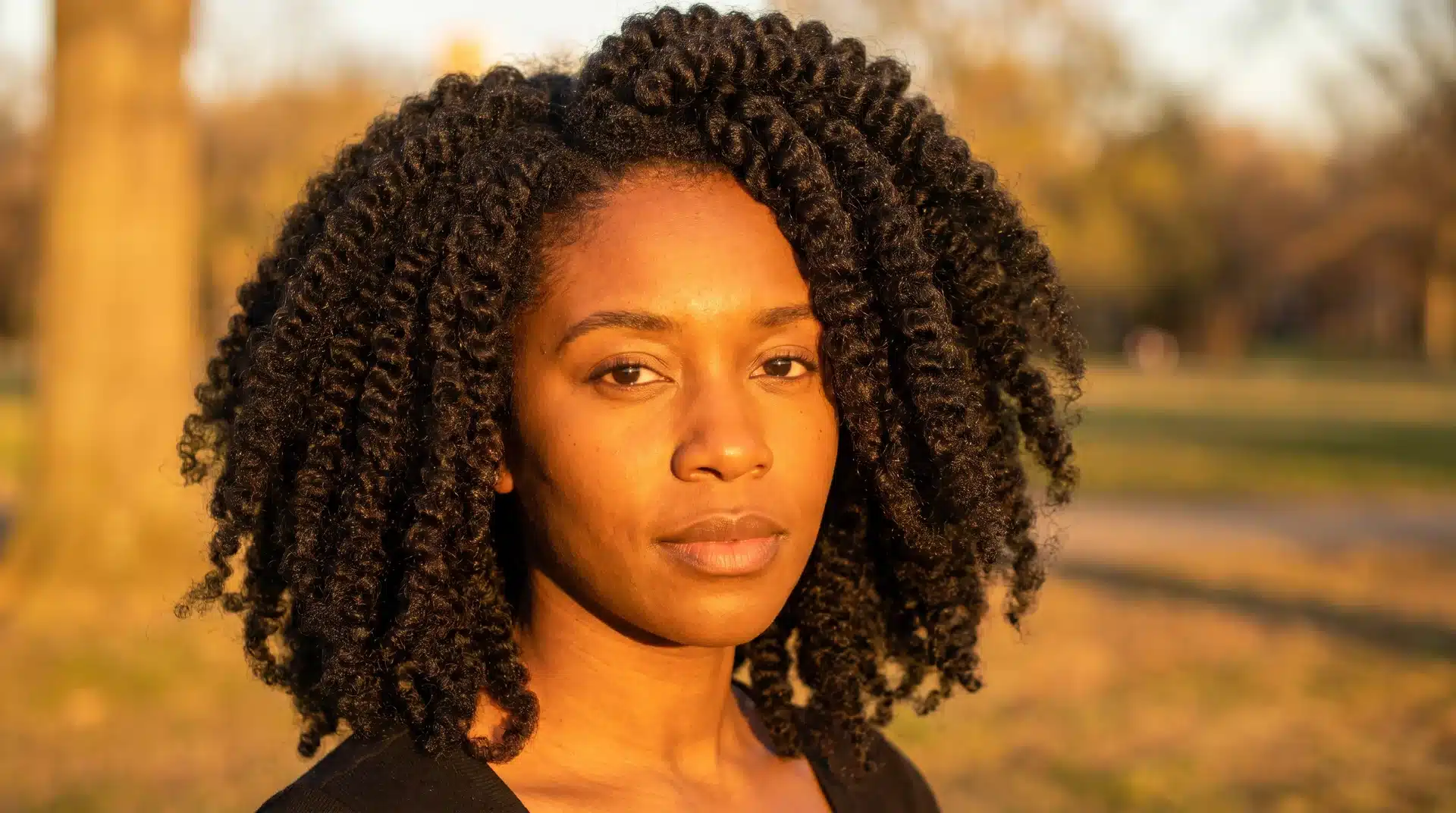 Black woman with a voluminous stretched twist-out and defined curl pattern in golden light.