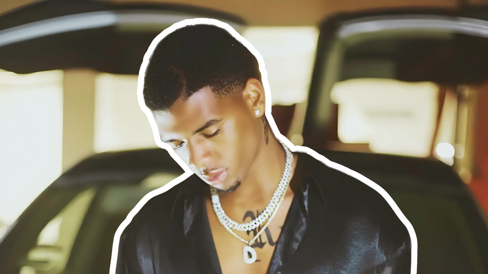 Wayne Deuce wearing a diamond chain necklace and black satin shirt representing his career as a photographer and creative director.