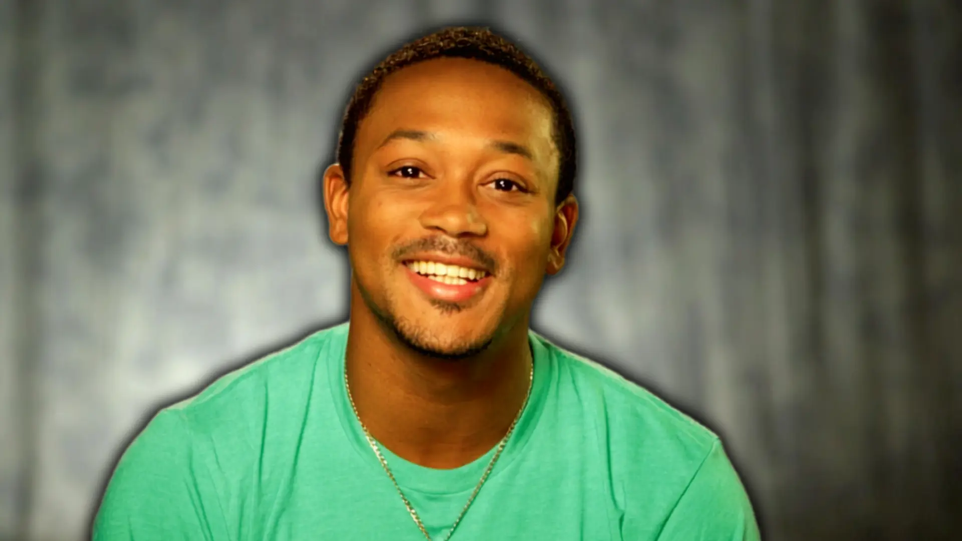 Romeo Miller smiling in a green shirt during an interview, Drew Sangster's longtime partner.