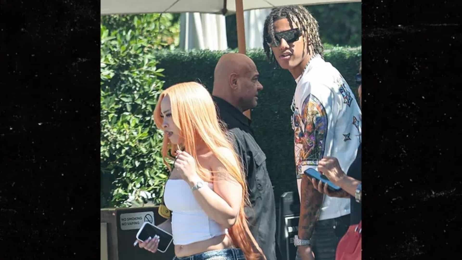 Ice Spice walking outdoors beside Diamant Blazi with other people in a public area.