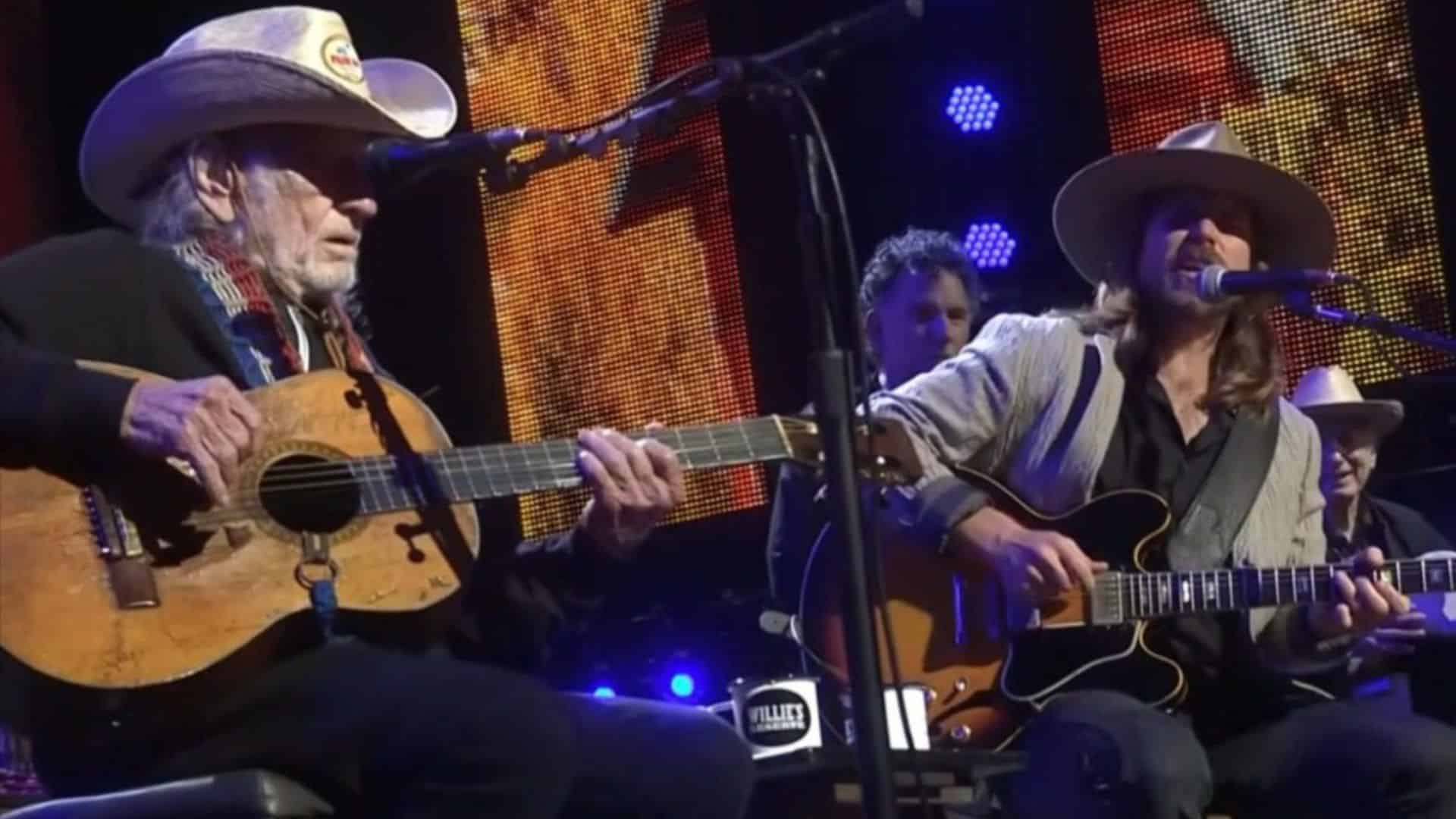 Johnny Depp performing with Willie Nelson on stage playing guitars during a live concert