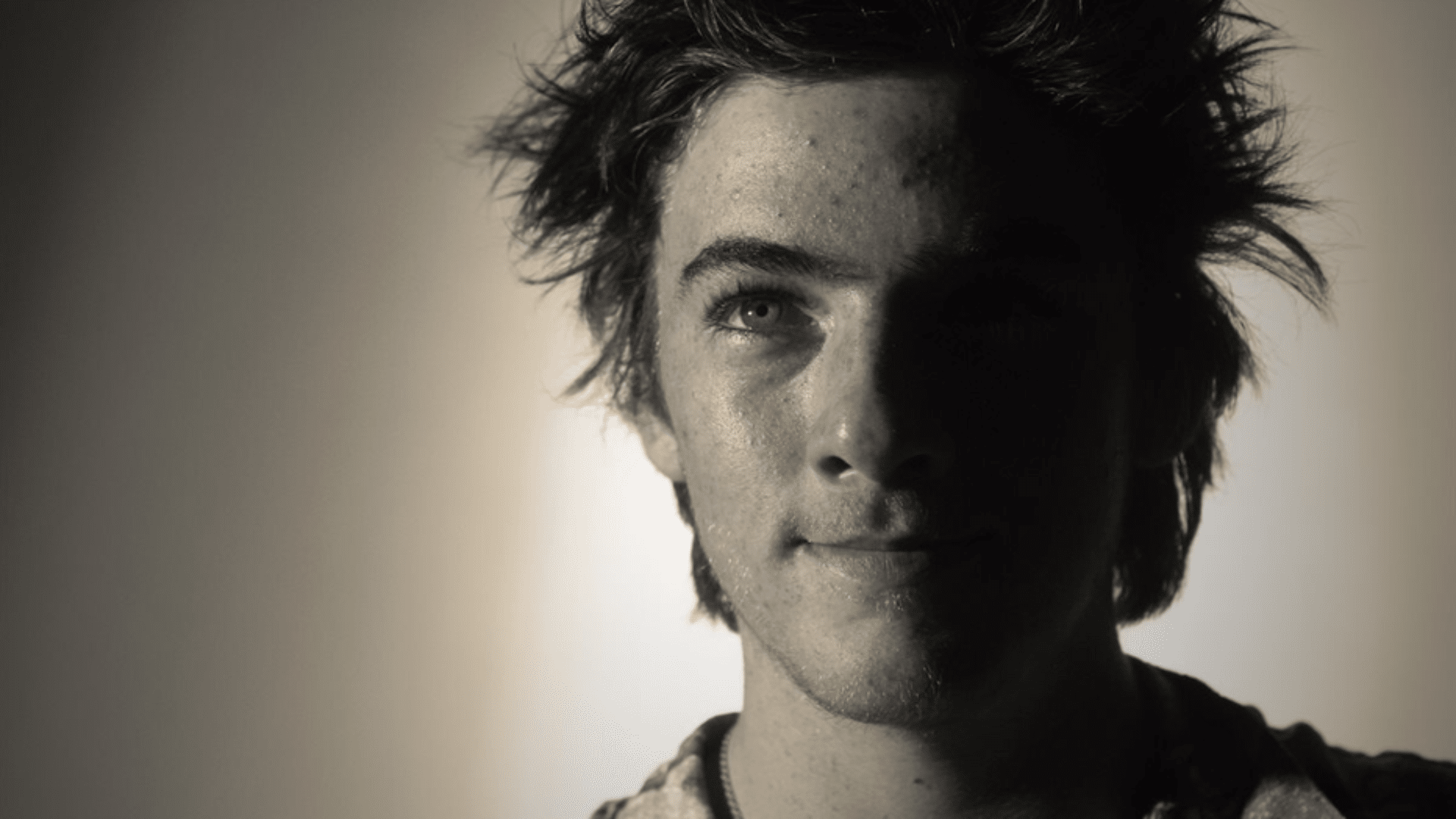 Young Angus Cloud, smiling casually, wearing relaxed clothing, with natural lighting highlighting his youthful features and playful, carefree demeanor.