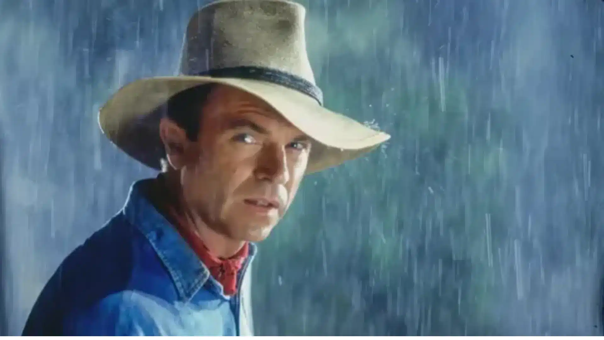 Dr. Alan Grant wearing a hat and raincoat during a storm scene in Jurassic Park.